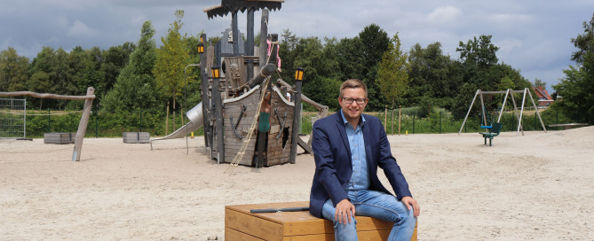 Bürgermeister Nils Anhuth testet die neuen Sitzgelegenheiten auf dem Traumspielpark.