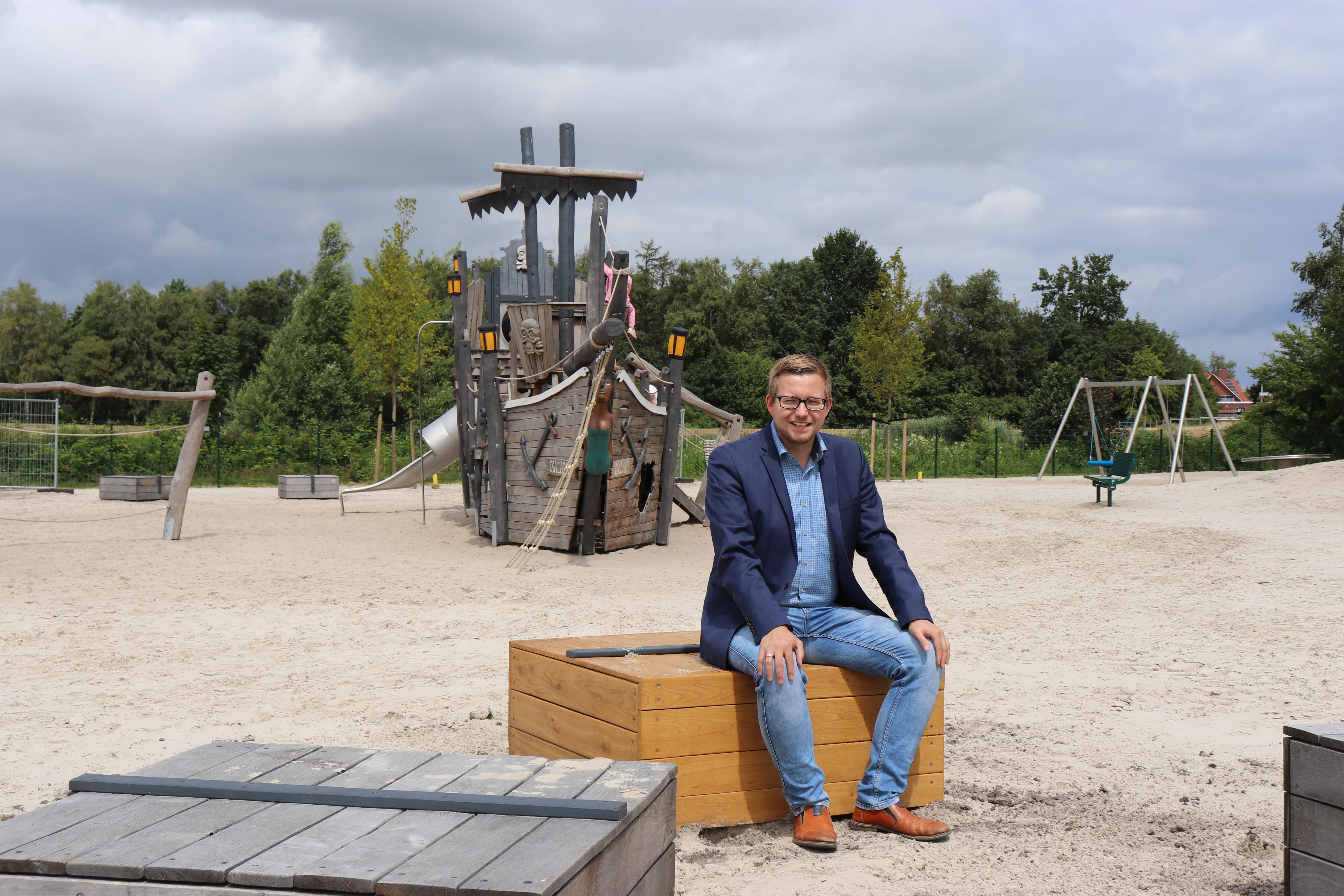 Bürgermeister Nils Anhuth testet die neuen Sitzgelegenheiten auf dem Traumspielpark.