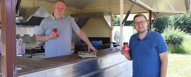 Oswald Eilers (links) und Bürgermeister Nils Anhuth trinken beim Aufbau des mobilen „Hafen-Cafés“ das erste Kaltgetränk. Aufnahme: Gemeinde Barßel