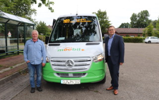 Wolfgang Böhmann (links, Fahrer des moobil+-Busses auf der Strecke in Barßel) und Bürgermeister Nils Anhuth vor dem moobil+-Bus. Bildquelle: Wlodarczyk/Gemeinde Barßel
