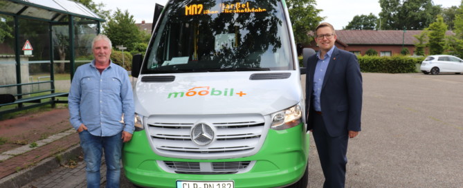Wolfgang Böhmann (links, Fahrer des moobil+-Busses auf der Strecke in Barßel) und Bürgermeister Nils Anhuth vor dem moobil+-Bus. Bildquelle: Wlodarczyk/Gemeinde Barßel