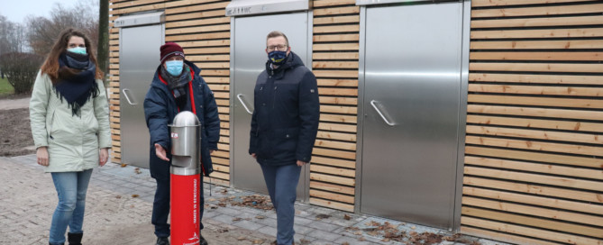 Präsentieren die neuen Containeranlagen inkl. Desinfektionsmittelspender (v.l.n.r.): Maja Peters, Hartmut Willhaus (beide vom Bauamt der Gemeinde Barßel) und Bürgermeister Nils Anhuth. Aufnahme: Wlodarczyk/Gemeinde Barßel