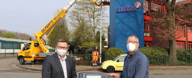 Bürgermeister Nils Anhuth (links) und Heinz-Georg Coners aus dem Bauamt präsentieren eine neue LED-Leuchte, die die Bauhofs-Mitarbeiter Ralf Deeken (Hintergrund, Mitte) und Markus Henken (oben) im gesamten Gemeindegebiet montieren. Aufnahme: Wlodarczyk/Gemeinde Barßel